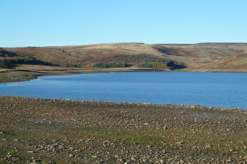 Low water levels at a reservoir, with an exposed stony shoreline